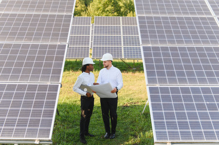 Engineers working on a solar power station, discussing new sustainable energy project plans in a...