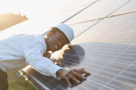 African american engineer wearing hard hat inspecting solar panel, ensuring clean renewable energy...