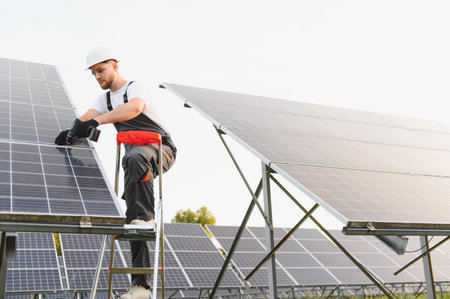 Engineer working on a solar panel array, installing elements for a renewable energy system in a...