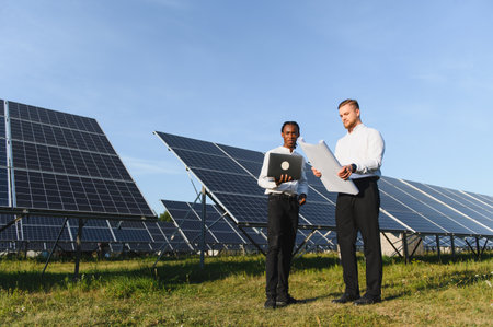 Two diverse engineers checking solar panel efficiency and development, working to advance...