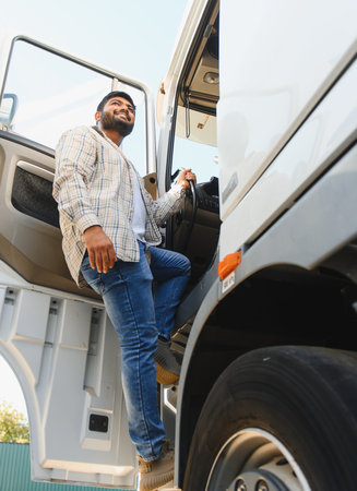 Young smiling Indian driver stepping into his truck cab, ready for long haul transport and logistics...
