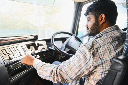 Indian man driving a commercial truck, adjusting controls on the dashboard. Representing...