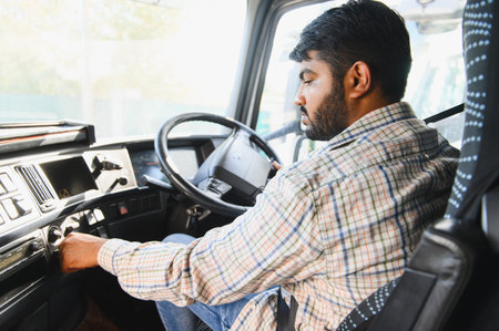 Indian man in plaid shirt turning key in ignition, preparing for transportation work inside a truck...