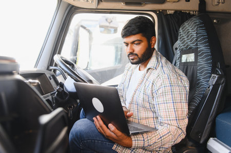 Truck driver using a laptop inside the cabin, managing remote work and digital logistics on the road