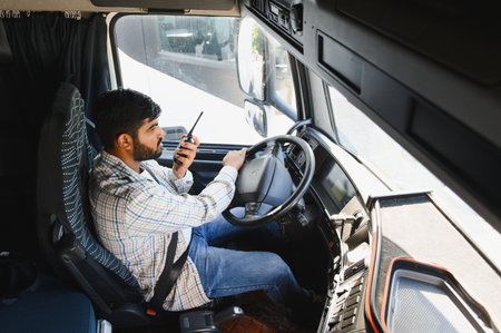 Truck driver operating vehicle and talking on a walkie talkie for essential communication during logistics operationsの写真素材