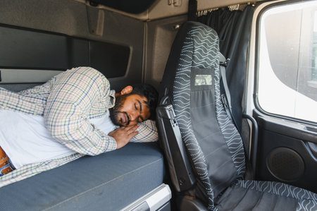 Indian man sleeping soundly on a bunk bed inside the truck cabin, taking a much needed break from...