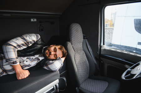Man resting in a truck cabin bunk. Driver taking a nap, recovering from fatigue on a long haul journeyの写真素材