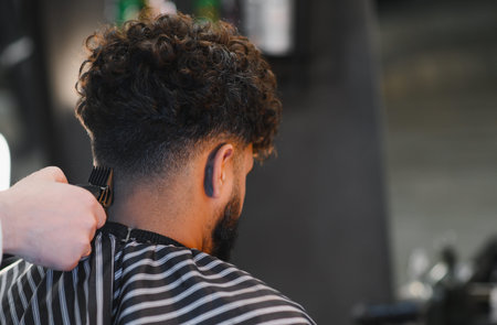 Man receiving a professional fade haircut at a barbershop. Clippers trimming the nape for a fresh...