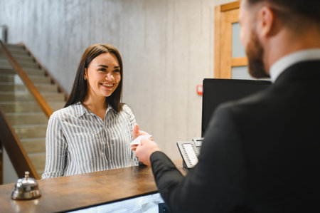 Smiling guest receiving room key or card from a hotel clerk at the front desk, highlighting hospitality serviceの写真素材