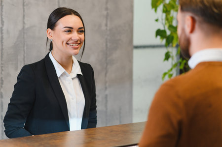 Friendly woman reception working customer service, welcoming hotel guest. Providing excellent hospitality and assistanceの写真素材