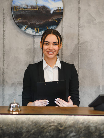 Young woman working as a hotel or business receptionist, offering professional hospitality service with a friendly smileの写真素材