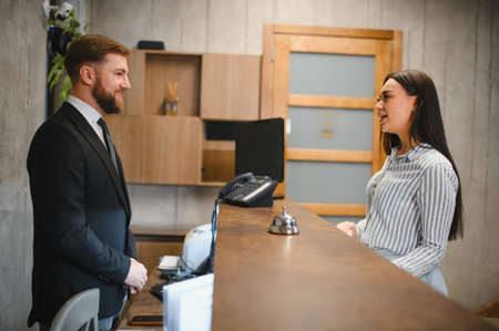 Businessman receiving professional service from a friendly female receptionist at a hotel or office lobby front deskの写真素材