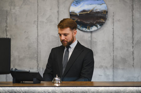 Professional man as a hotel receptionist or concierge providing hospitality service at a reception desk, working at a modern officeの写真素材