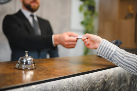Guest completing check in process, receiving hotel room key card from receptionist at the front desk, showcasing hospitality serviceの写真素材