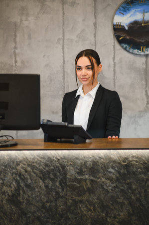 Young woman working as a hotel concierge or front desk receptionist, providing customer service in a professional business environmentの写真素材