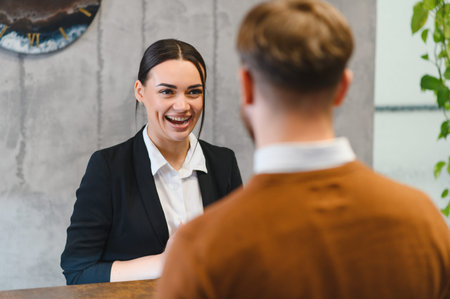 Woman in professional attire smiling, laughing, and interacting with a man during a business meeting or interview at a modern officeの写真素材