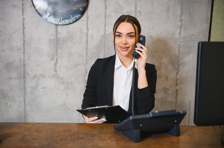 Smiling young businesswoman working as a receptionist, communicating with clients and providing customer service in an office settingの写真素材
