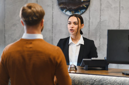 Female hotel receptionist assisting male guest at the counter. Providing excellent customer service during check in or inquiryの写真素材