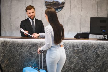 Traveler arriving at a hotel, interacting with receptionist, completing check in process. Hospitality and service conceptの写真素材