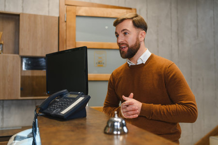 Friendly male receptionist providing excellent customer service at a hotel or office reception area. Hospitality and helpfulness conceptの写真素材