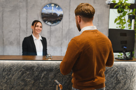 Guest arriving at modern hotel, enjoying friendly hospitality and professional service from female receptionist at check inの写真素材