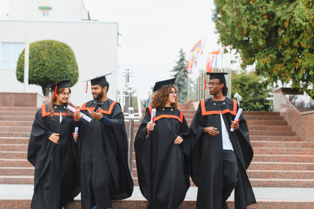 Group of multi ethnic graduates walking down university steps, celebrating academic achievement and a bright futureの写真素材