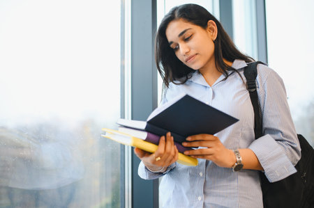 Young Indian woman holding books, reading information to learn and prepare for studies and building a careerの写真素材