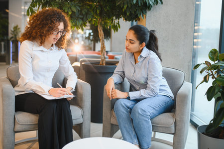 Female psychologist providing therapy to an Indian woman, engaging in a professional mental health consultationの写真素材