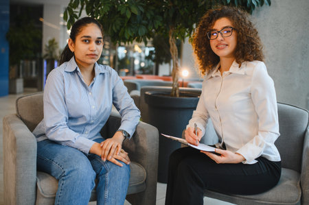 Psychologist providing professional counseling to an Indian woman seeking mental health support in a modern officeの写真素材
