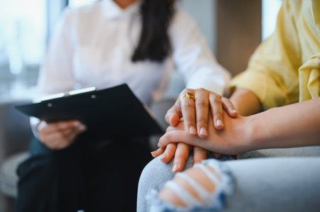 Female psychologist providing emotional support, holding hands with a patient, demonstrating empathy and trust during a therapy sessionの写真素材