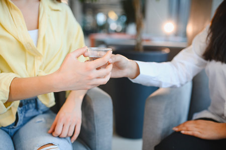 Psychologist showing empathy and support by offering water to a distressed female patient during a therapy sessionの写真素材