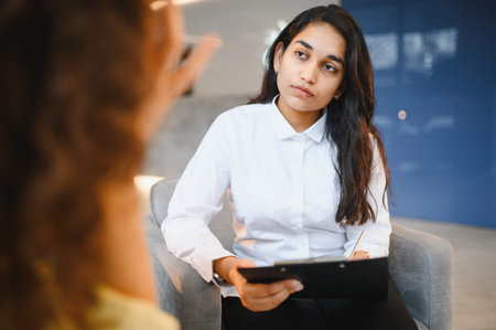 Indian female psychologist actively listening to her patient, providing professional counseling and mental health supportの写真素材