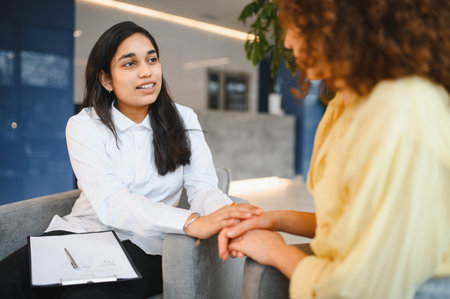 Indian psychologist providing support and empathy to a young patient, offering mental health care during a counseling sessionの写真素材