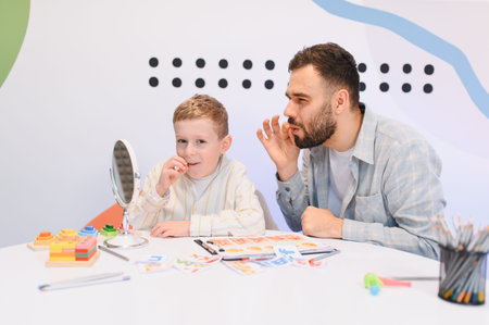 Child practicing articulation exercises with a speech therapist. Improving communication skills and addressing developmental needs in a bright roomの写真素材