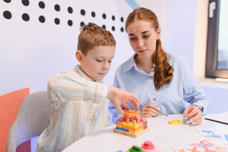 Young boy building a colorful wooden puzzle with teacher guidance, fostering early childhood education and cognitive developmentの写真素材