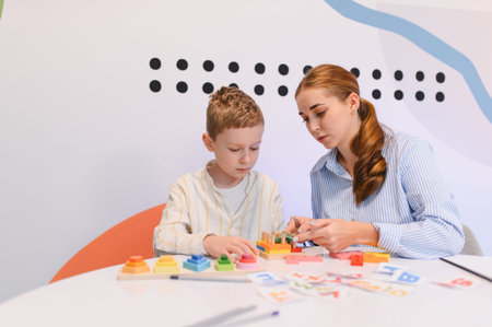 Teacher and boy engaging in a learning activity with colorful educational toys and cards, developing cognitive skillsの写真素材