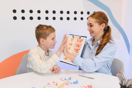 Young boy engaging in a speech therapy session, learning with a therapist, high giving for encouragement and positive reinforcementの写真素材