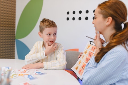 Young boy learning with a speech therapist. The therapist is showing mouth exercises while the child practices pronunciationの写真素材