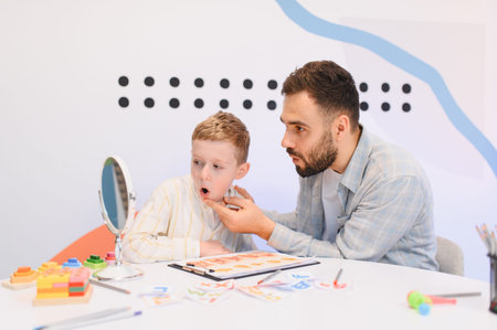 Speech therapist helping a young boy with speech exercises, practicing articulation and communication skills during a therapy sessionの写真素材