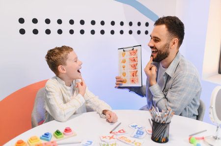 Speech therapist and young child practicing articulation, mirroring mouth movements and using visual aids for communication developmentの写真素材