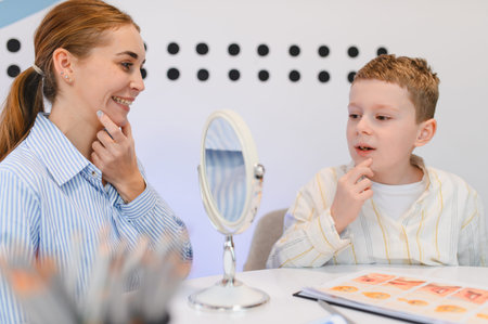 Speech therapist and boy working on articulation and communication skills using a mirror during a...