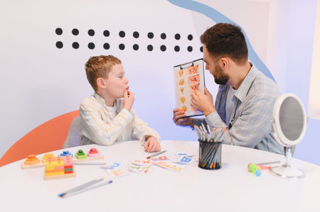 Speech therapist working with a young boy, using a visual aid for speech correction and articulation exercises in a clinicの写真素材