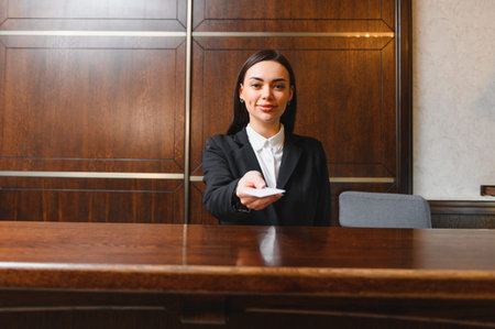 Young smiling woman working at luxury hotel reception desk, providing quality customer service and hospitalityの写真素材