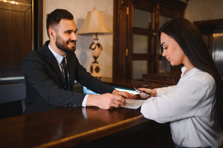 Hotel receptionist helping a female guest at the front desk, completing paperwork for check in serviceの写真素材