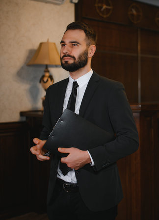 Male professional in a business suit holding a clipboard, working as a receptionist or manager in a luxurious hotel lobbyの写真素材