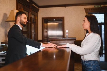 Hotel receptionist helping a female guest at the reception desk in a luxurious lobby, providing customer service during check inの写真素材