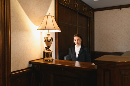 Young female receptionist offering service at a luxurious reception desk in elegant hotel lobby environmentの写真素材