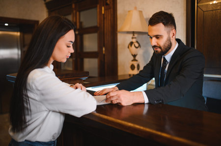 Hotel receptionist assisting a female guest completing paperwork at the front desk, providing excellent customer serviceの写真素材
