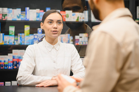 Young female pharmacist providing professional advice to a male customer about health products and medicine at the drugstore counterの写真素材