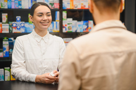 Smiling pharmacist in white coat medication providing to a customer at a pharmacy, focusing on service and healthcareの写真素材
